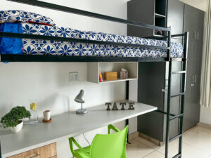 Side view showcasing a bunk bed with adjacent storage cupboards for clothes and belongings at Tate Village
